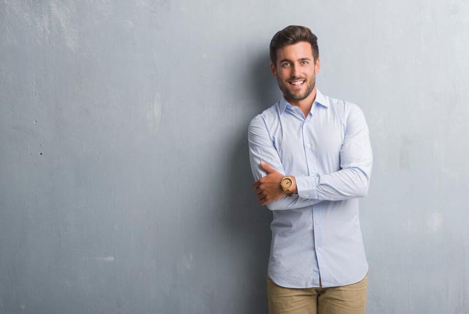 A guy is smiling against a grey background