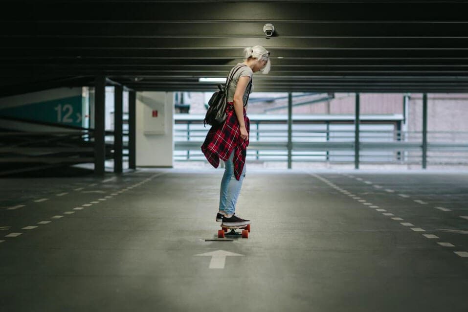 A girl with a flannel wrapped around her waist is skateboarding.
