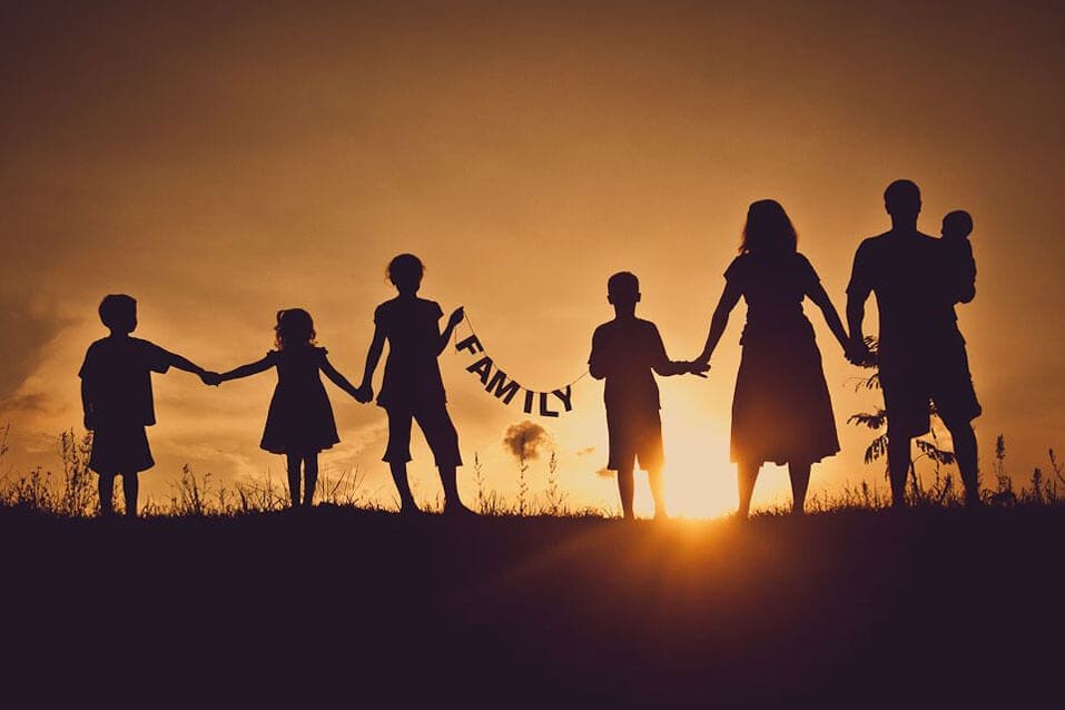 Family holding a family sign in sunset