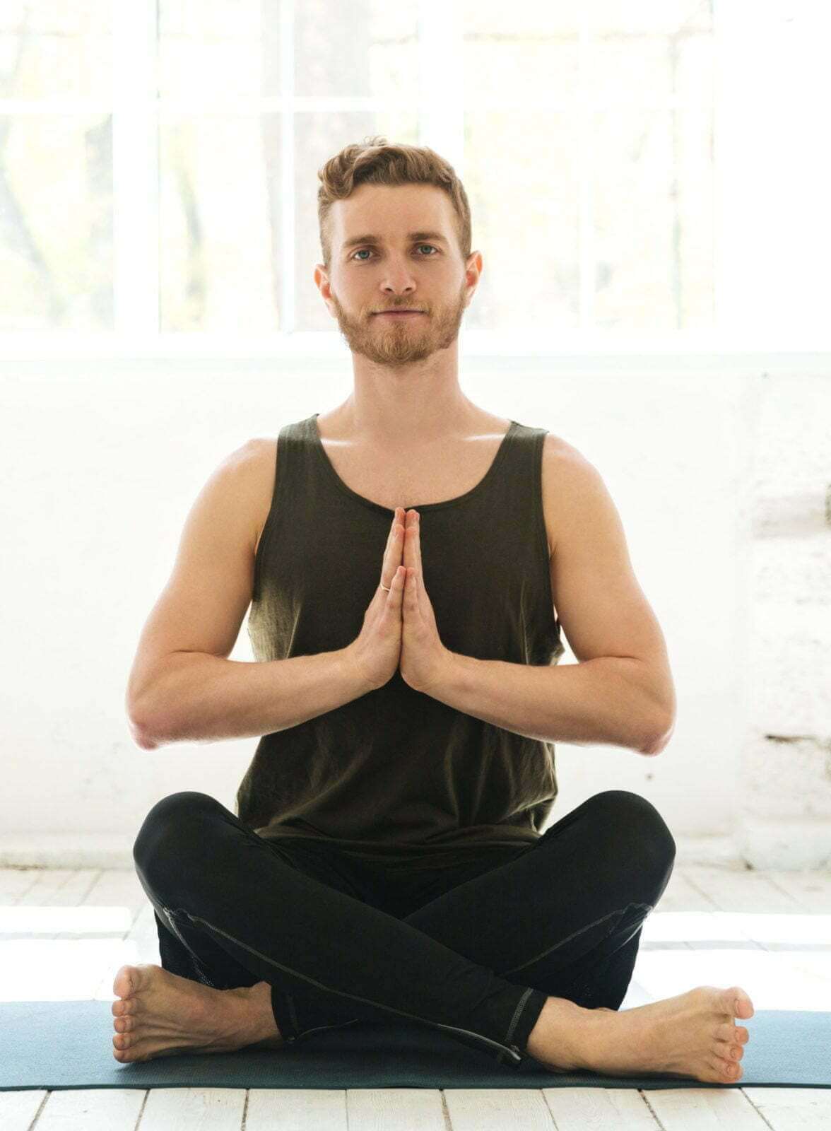 A man in a tank top practicing yoga in a rehab center.