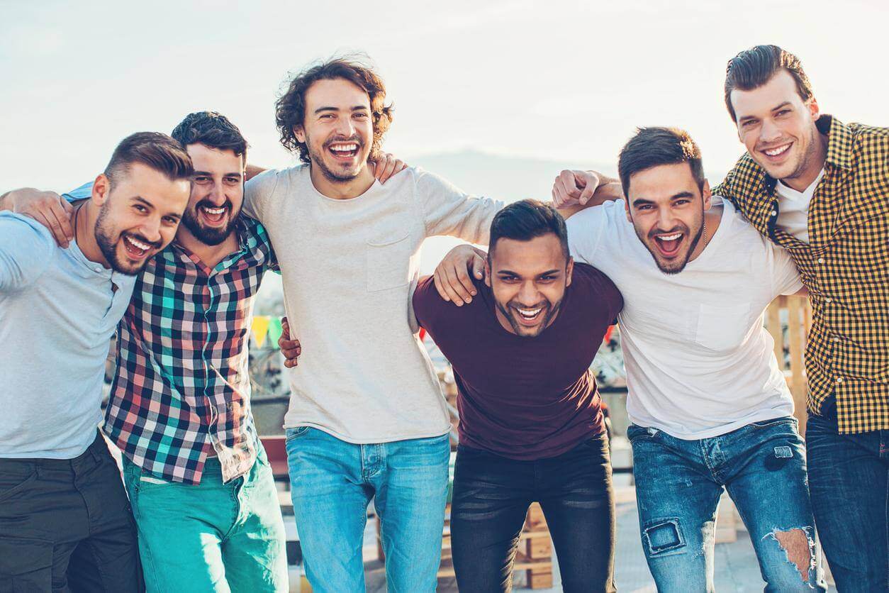 A group of men in an addiction recovery center, standing together and laughing.