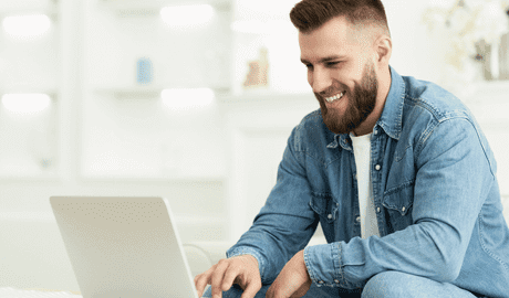 A man with a beard using a laptop in a men's only rehab.