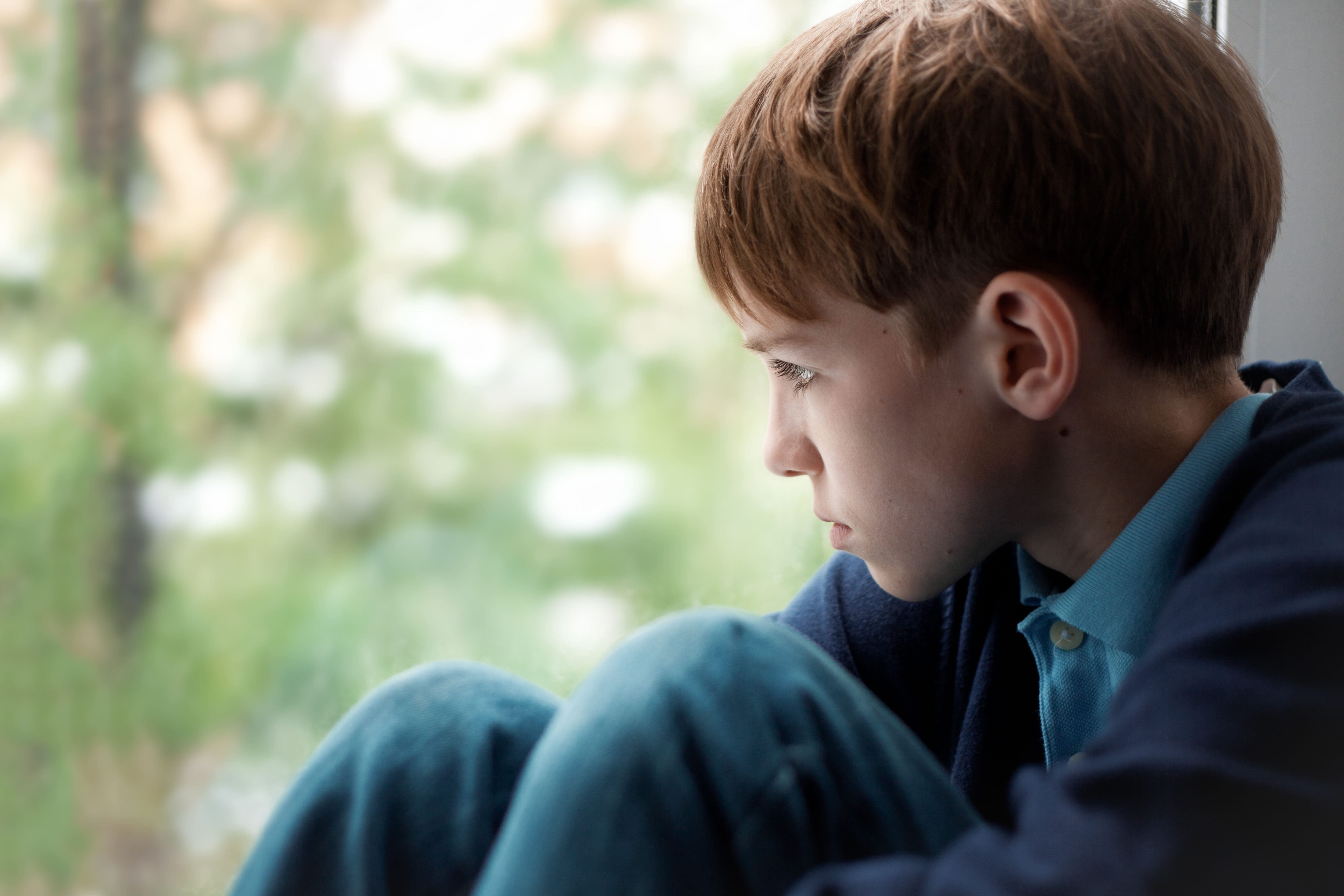 A young boy looking out of a window at an addiction recovery center.