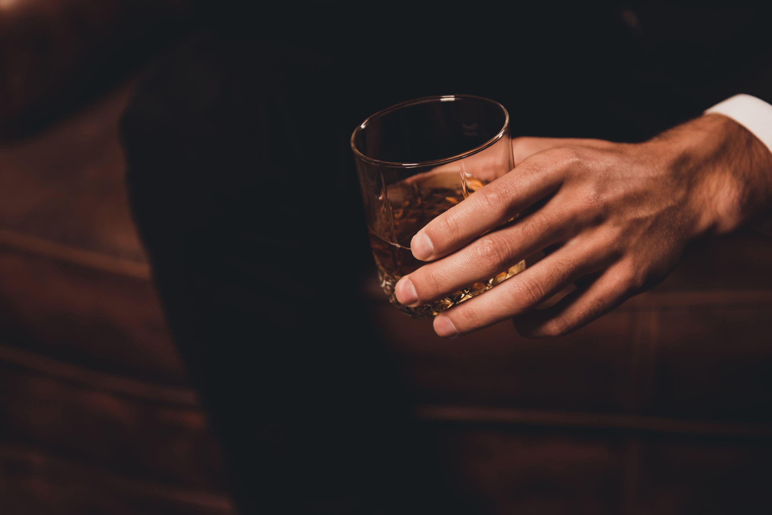 A man in a suit holding a glass of whiskey at an addiction recovery center.