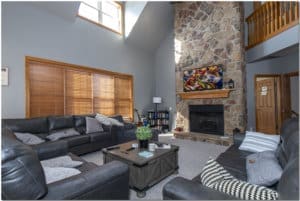 A cozy living room with a stone fireplace, perfect for relaxation and gathering around with friends or family.