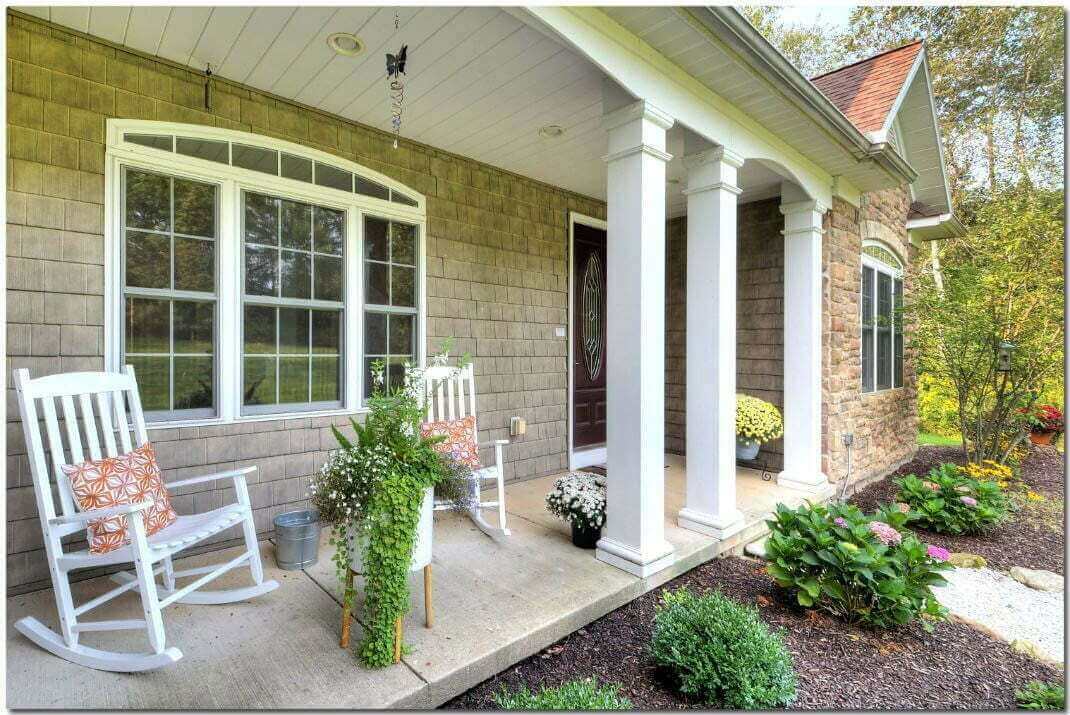 A serene front porch with rocking chairs and blooming flowers.