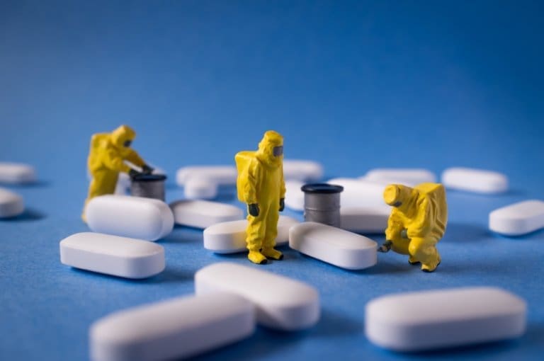 A group of people in yellow suits standing next to a bunch of pills at an inpatient treatment facility.