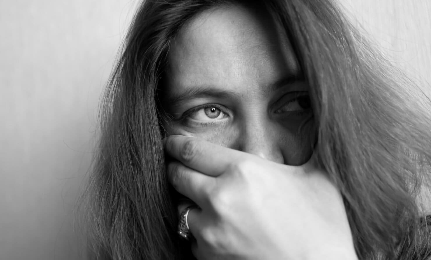 A black and white photo of a woman in rehab covering her face.