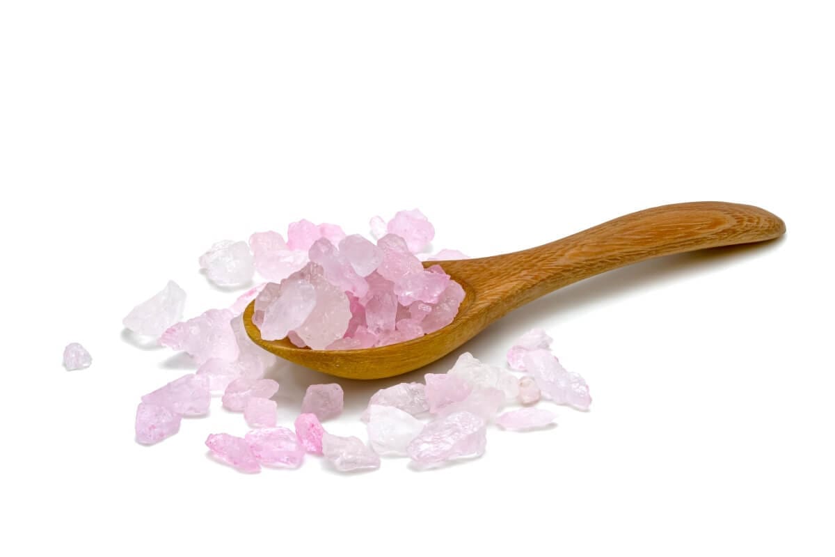 Pink salt in a wooden spoon on a white background, perfect for an addiction recovery center or rehab facility.