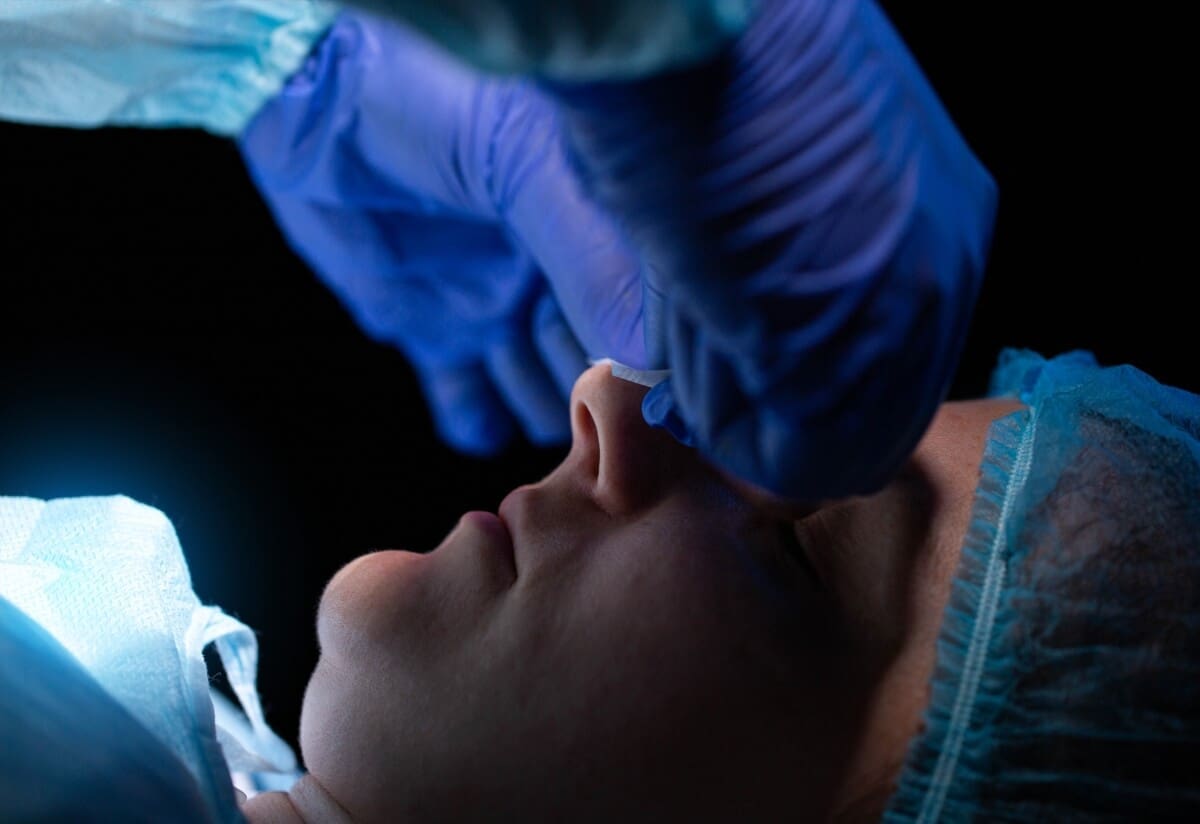 A woman's nose is being operated on by a surgeon in an outpatient program.