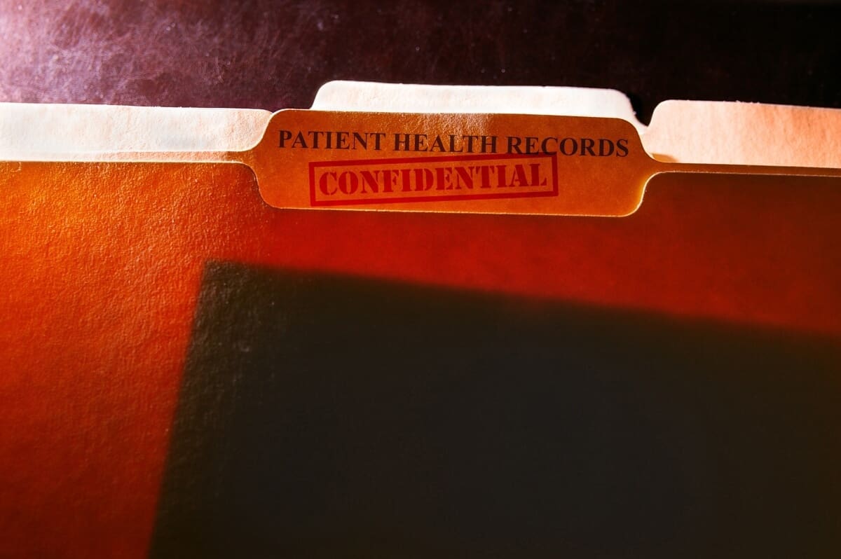 A file folder containing confidential patient health records for an outpatient program.
