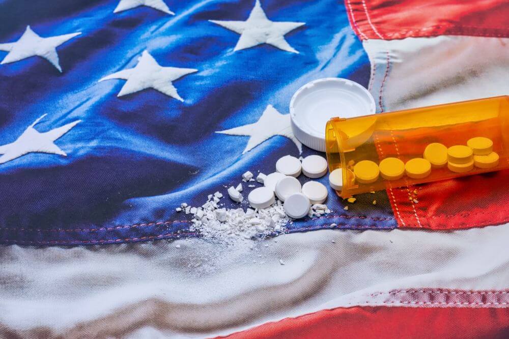 A bottle of pills on an American flag, representing the struggle and journey of addiction recovery in an outpatient program.