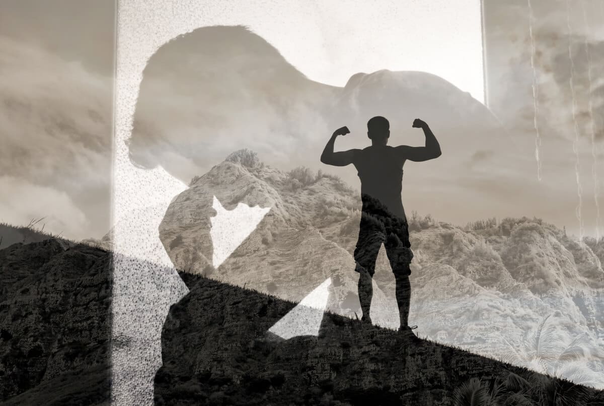 A silhouette of a man standing on top of a mountain, symbolizing triumph and accomplishment in addiction recovery.
