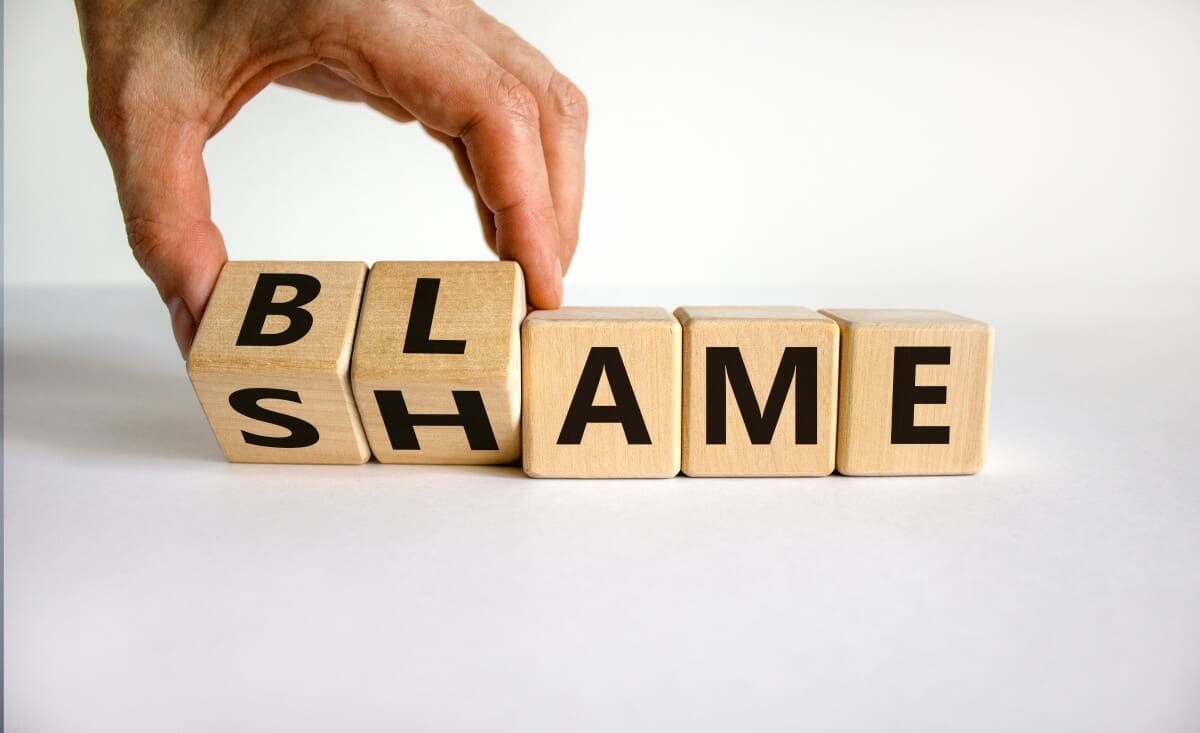 A person holding wooden cubes with the word shame on them, reflecting their journey through inpatient treatment.